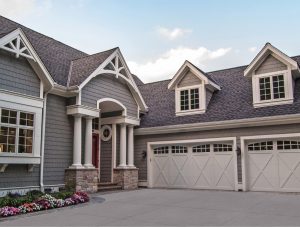 a gray house with with 2 white garage doors